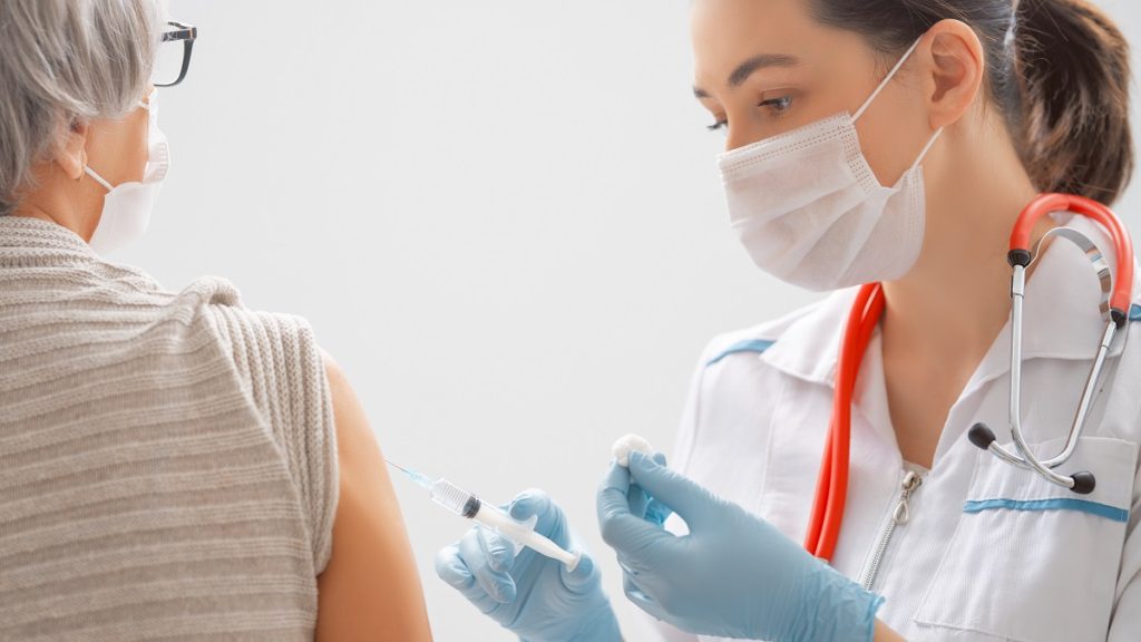 doctor giving a senior woman a vaccination BZT5DML