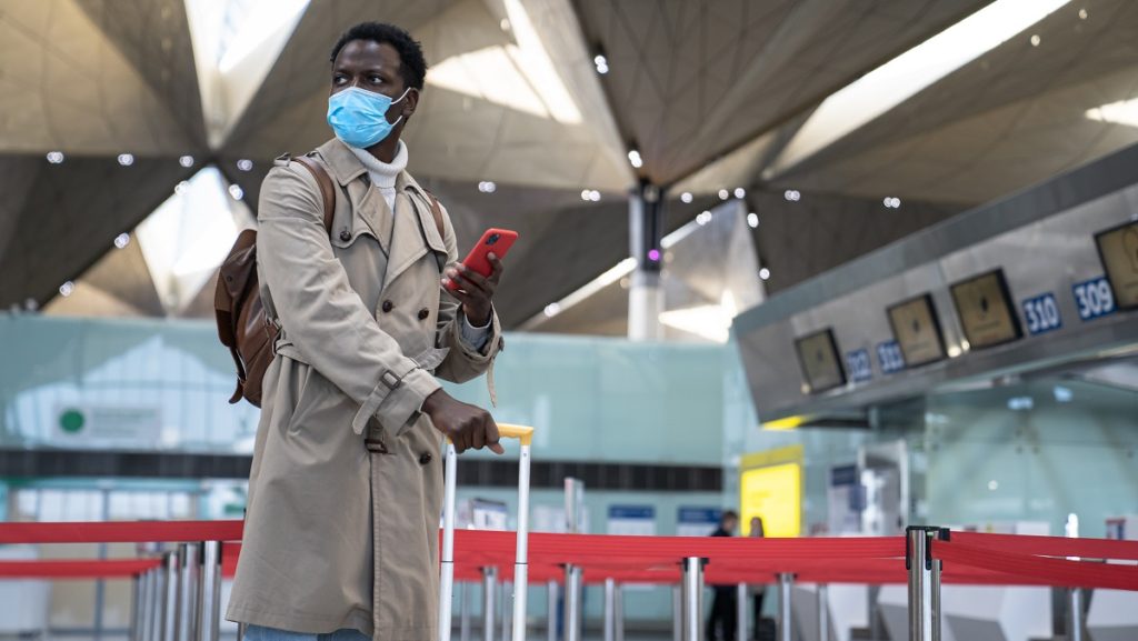 black man standing airport wearing face protective mask during virus epidemic covid 19