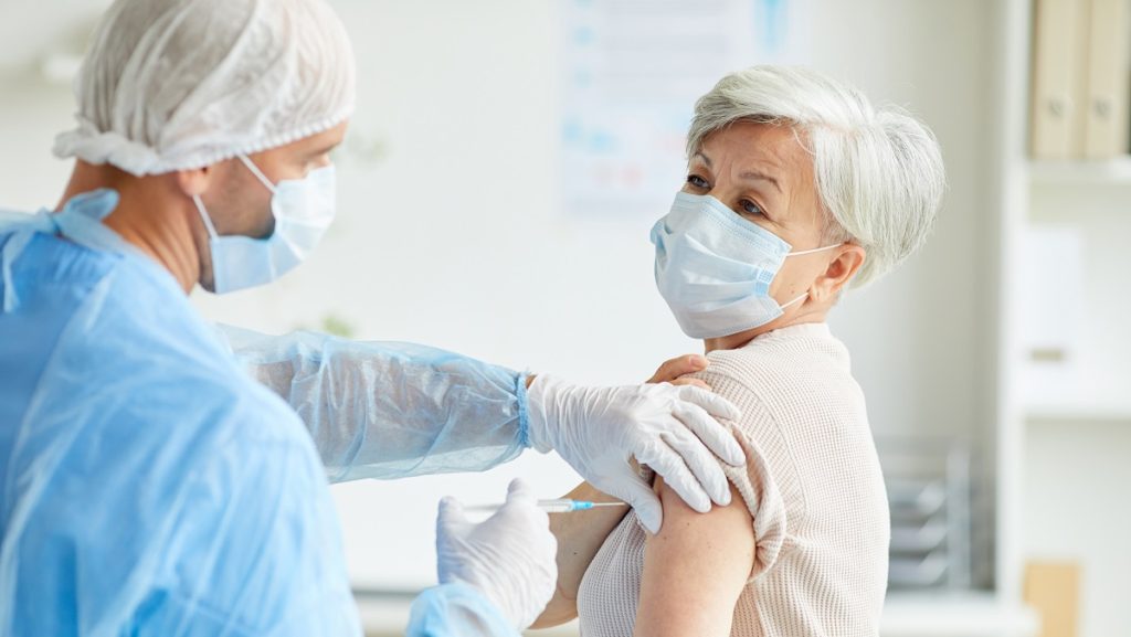 doctor giving covid 19 vaccine to woman NSXXKRP