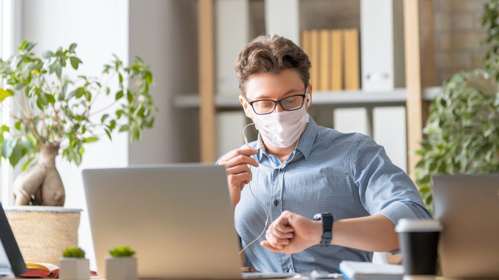 man in face mask is working on a laptop D22TGZL