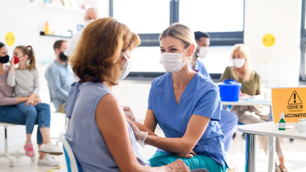 woman with face mask getting vaccinated coronaviru MXRLAKX