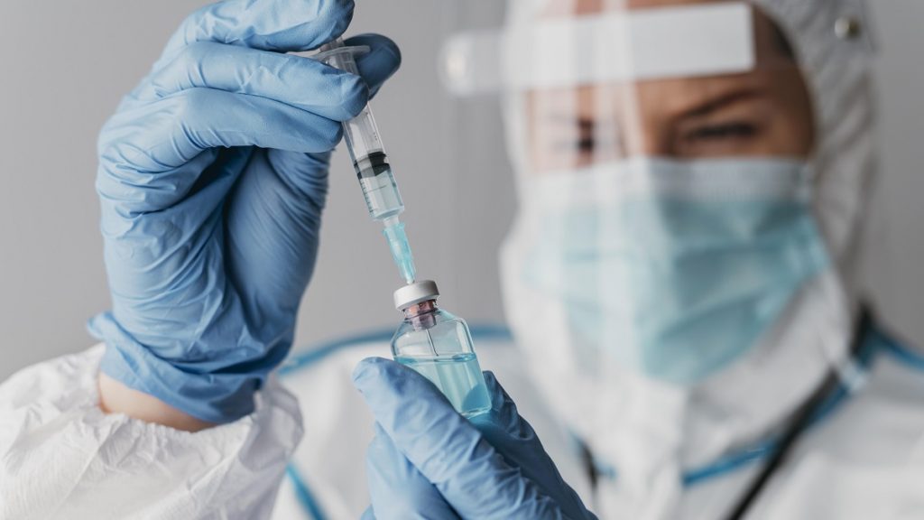 doctor holding preparing vaccine while wearing protective equipment 1