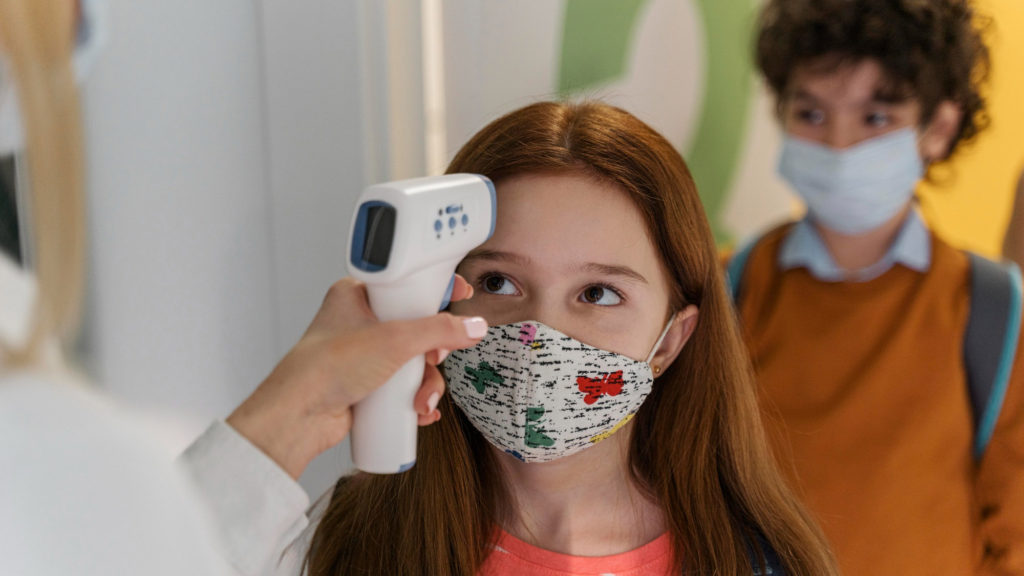 teacher with medical mask checking children s temperature school copy