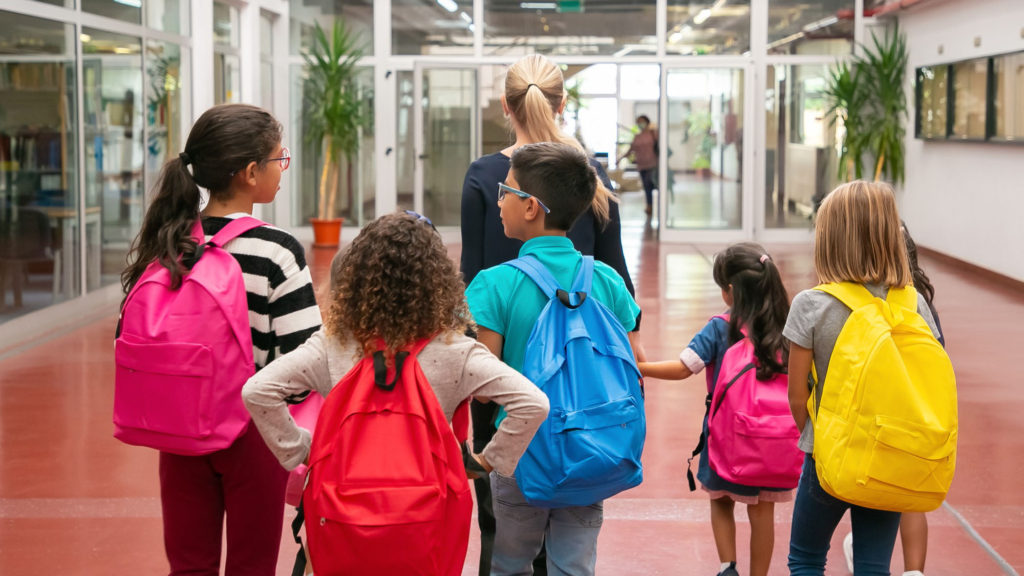 group children with female teacher walking school corridor copy