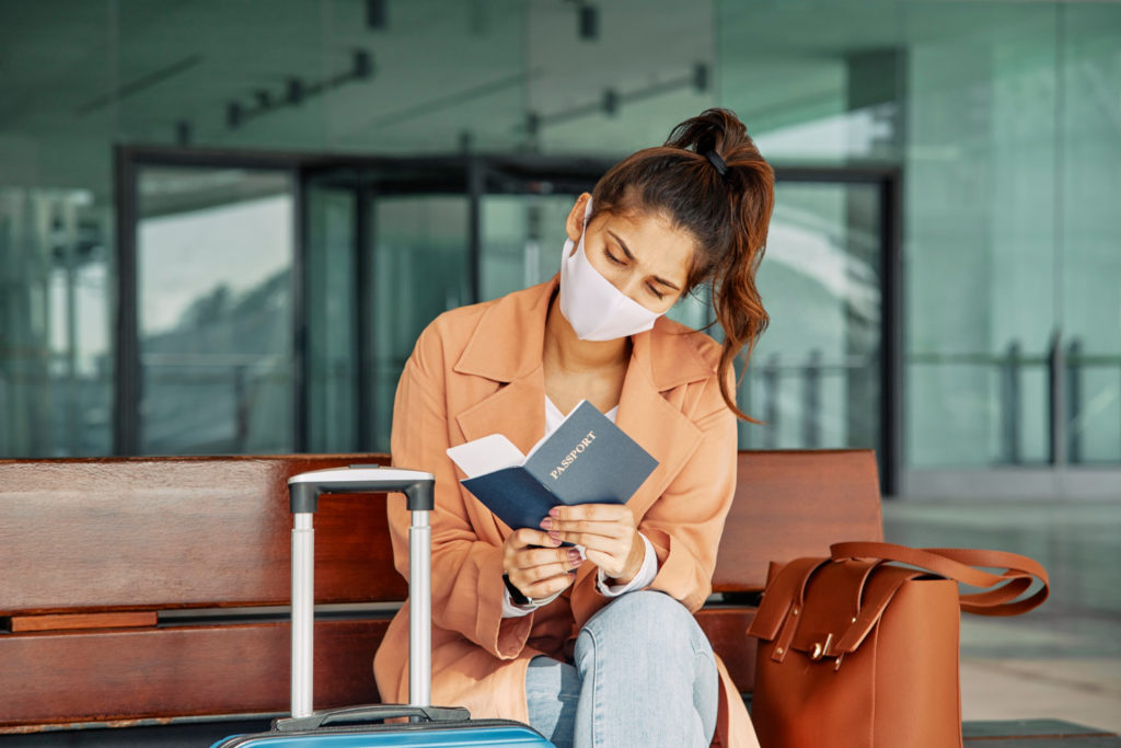 woman with medical mask checking her passport airport during pandemic copy