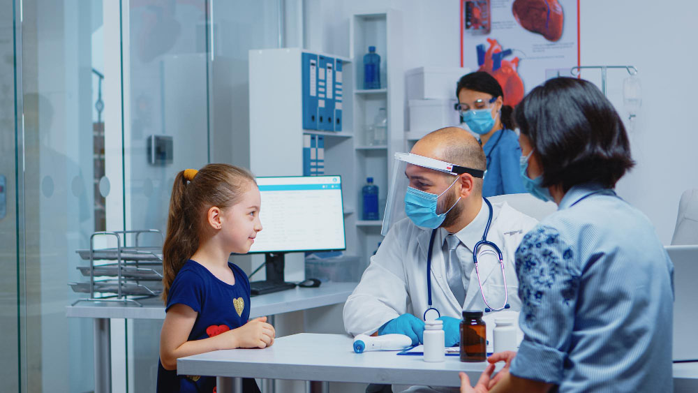 cheerful pediatrician smiling little girl during medical visit specialist medicine with protection mask providing health care services consultation treatm copy