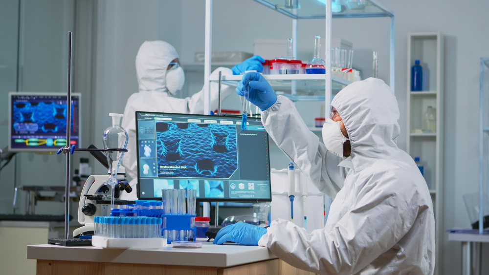 neurologist with ppe suit working vaccine development equipped laboratory typing pc team examining virus evolution using high tech research treatment