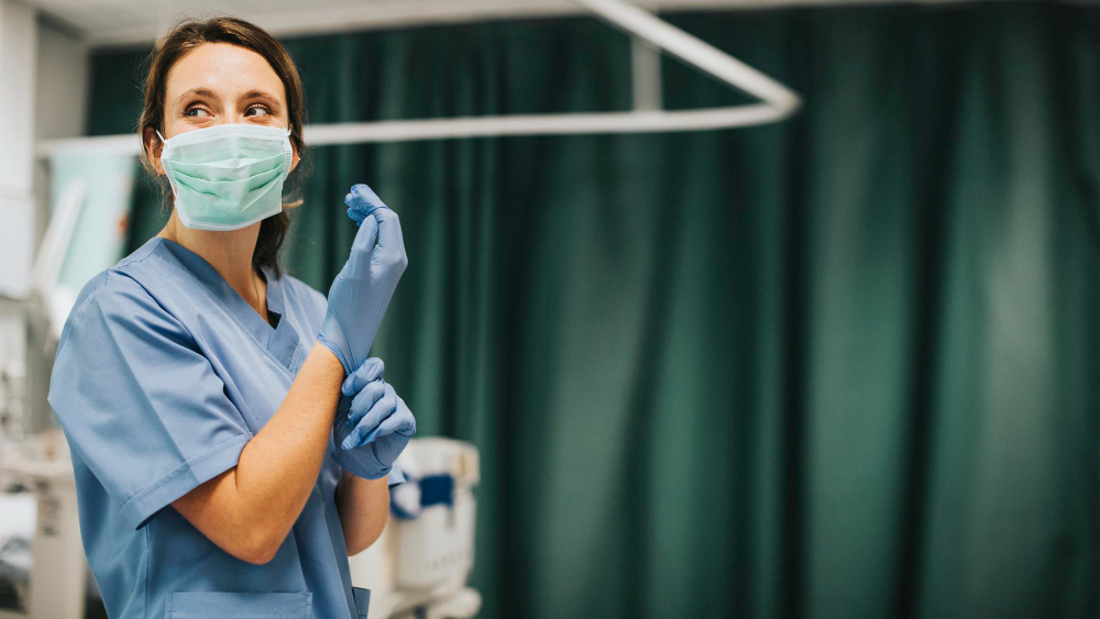 female nurse with mask putting gloves preparing cure coronavirus patient