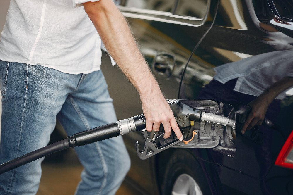 handsome man pours gasoline into tank car