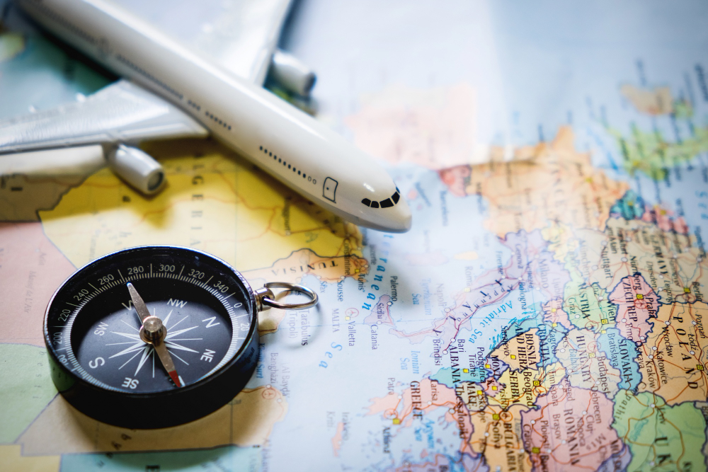 selective focus miniature tourist compass map with plastic toy airplane abstract background travel concept