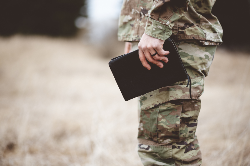 shallow focus shot young soldier holding bible field