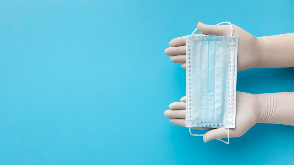 top view hands with gloves holding medical mask with copy space