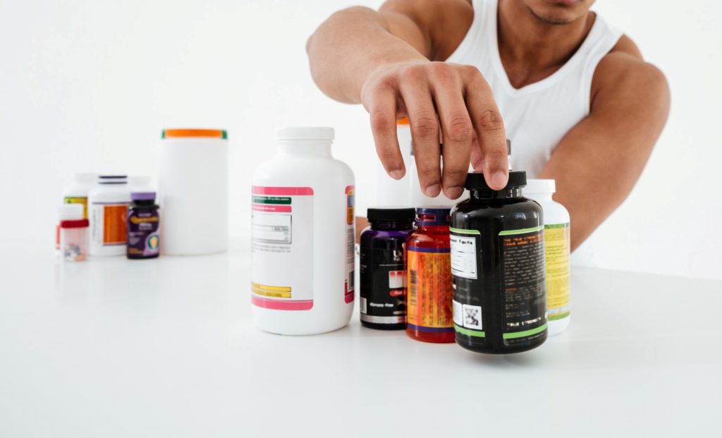 sportsman standing white wall holding vitamins 2