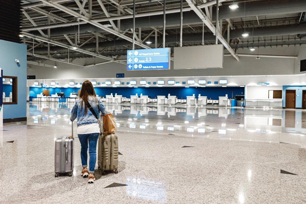 woman walks along airport with suitcases