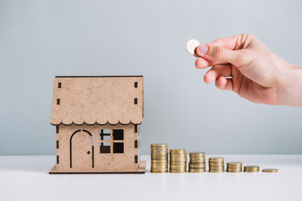 person s hand stacking coins near house model