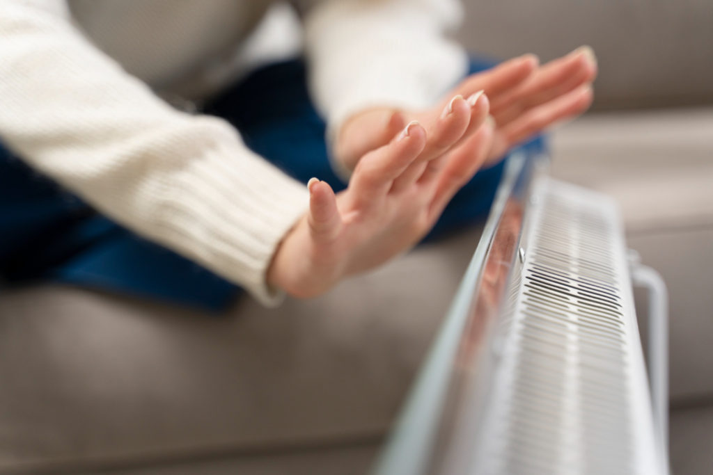 close up hands warming up near heater