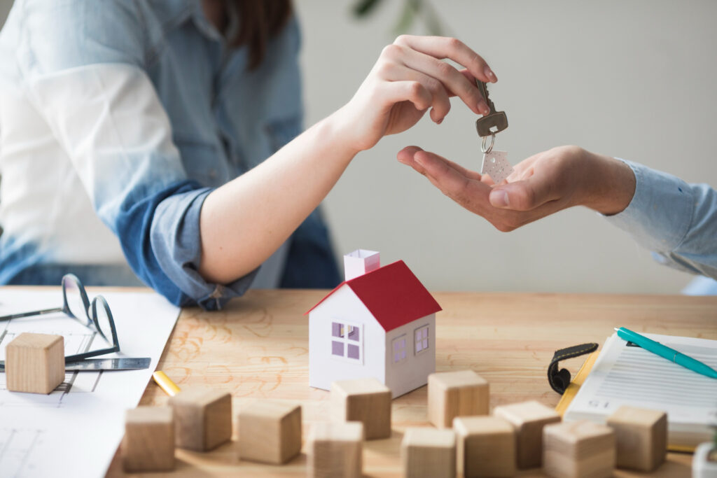 close up woman s hand giving house key man wooden table